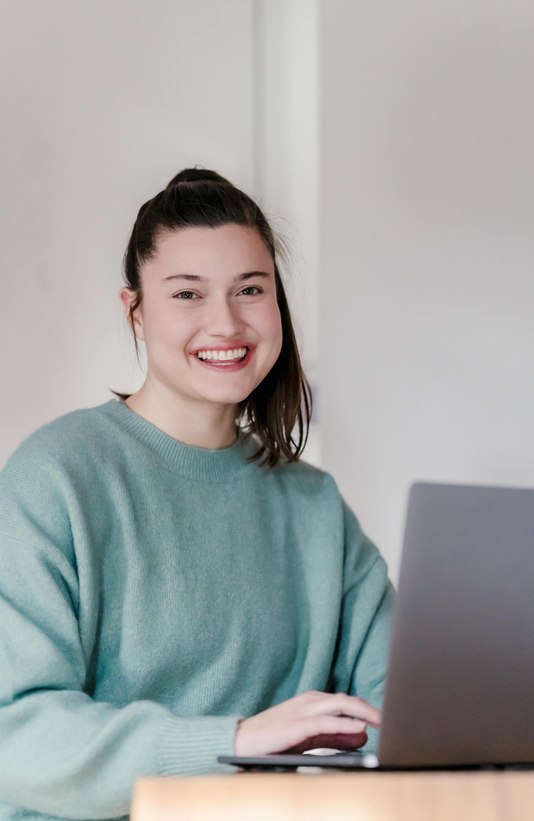 Happy young adult using a laptop on a couch at home